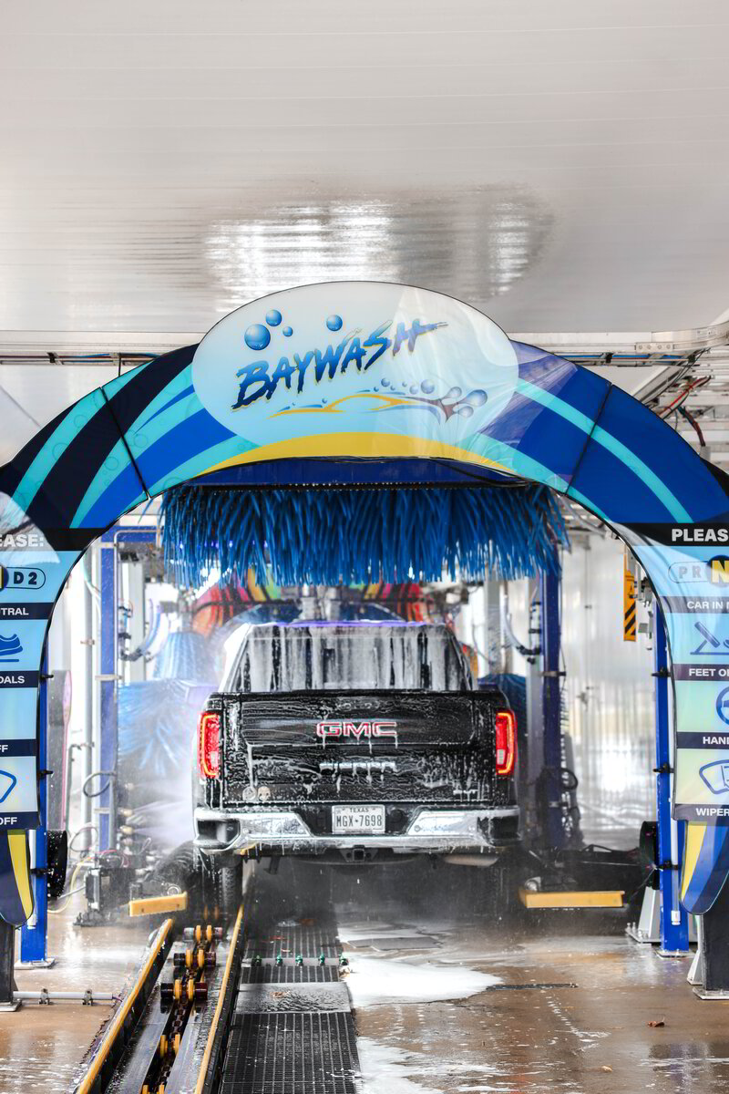 A vehicle passing under the branded Baywash wash arch